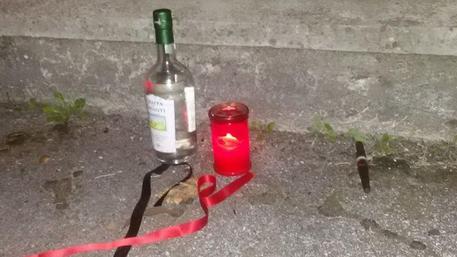 Riti africani a Massa. Grappa, sigari e lumini lasciati sul marciapiede