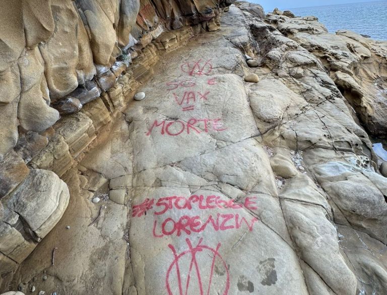 Scritte no vax a Cala Martina, la comunità di Scarlino indignata. Il Comune: “Rimuoverle non sarà semplice”